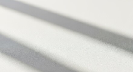 Diagonal shadows cast across a plain white surface, creating minimalist abstract shapes.