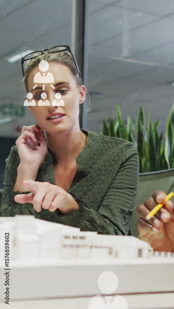 Poster animation of network of profile icons over diverse man and woman discussing over a model at office