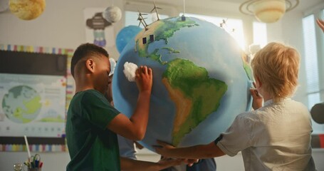 Renewable Energy STEM Class: Elementary School Students Attaching Miniature Models of Clouds to Globe. Female Teacher Explaining Science and Energy Sources to Smart Diverse Kids in Modern Classroom. - Powered by Adobe