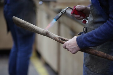 Man is holding a wooden stick with a flame on it