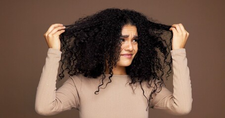 Curly, hair and woman in studio with damage, frizz problem and dry texture on brown background....