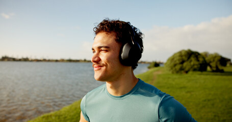 Headphones, happy man or athlete thinking in lake for outdoor training, workout or exercise. Smile, inspiration or sports runner on break for streaming radio, music audio or fitness podcast to relax