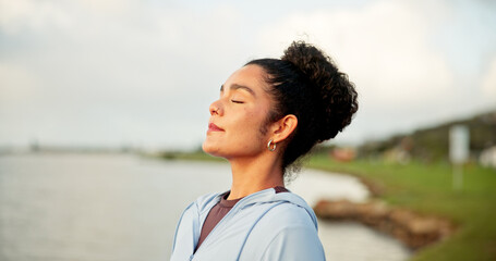 Breathing, exercise and meditation with woman at lake in nature for awareness, balance or wellness. Eyes closed, fitness and zen with calm person outdoor in park for inner peace or mindfulness