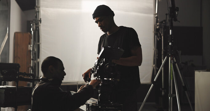 Film, production and videographer speaking to director in studio for filming or footage update. Conversation, discussion or planning with cameraman and producer on set for behind the scenes shooting