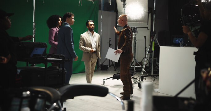 Director, script and instruction to actor on set for creative guidance, cast direction and tips. People, filming team and producer with green screen for movie production, acting help and assistance