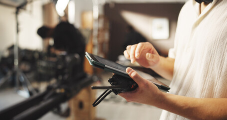 Hands, person and tablet for filming backstage for editing video, review script and shooting catalog. Male director, digital app and checklist, scene footage and performance guide of movie production