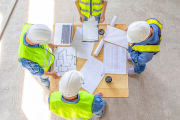 top view of engineers team meeting and discussing by using laptop,blueprint and documents on table...