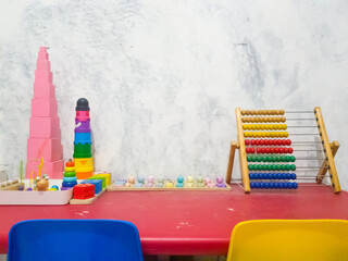 A colorful preschool play area featuring educational wooden toys, including an abacus, stacking...