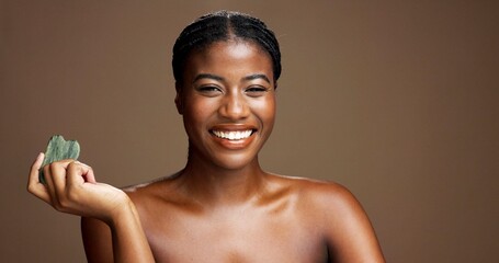 Beauty, face and gua sha with black woman on studio space for dermatology or wellness. Jade stone,...