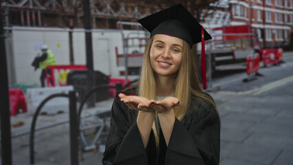 Young woman in graduation gown smiling at a construction site, symbolizing new beginnings and...