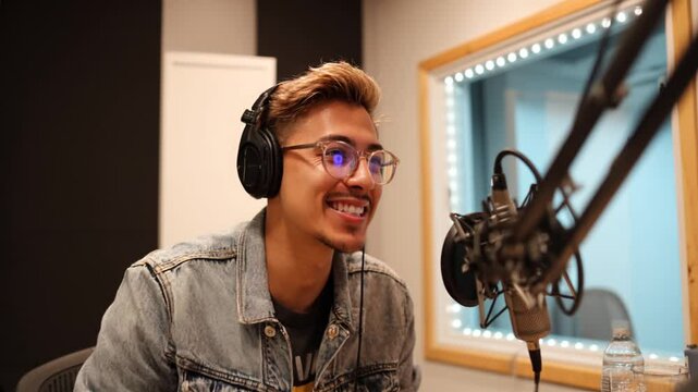 Young man recording a podcast in a professional studio with headphones and microphone
