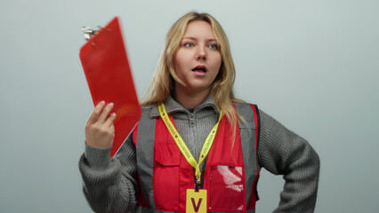 Woman volunteer discussing on white background holding red clipboard, wearing gray sweater and red...