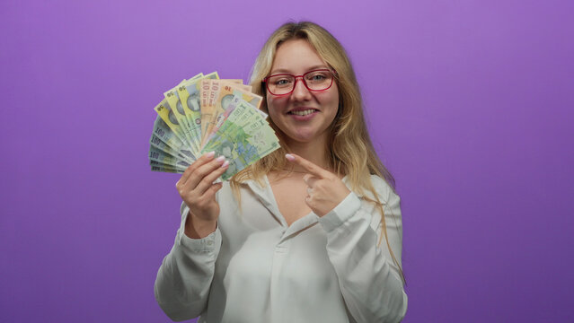 Young woman holding romanian banknotes over a vibrant purple background, smiling confidently to convey wealth and financial success.