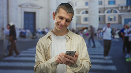 Man using smartphone on bustling street, featuring outdoor urban backdrop with people crossing in...