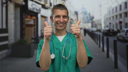 Caucasian man in doctor uniform with stethoscope and cheerful expression gives thumbs up on an urban street.