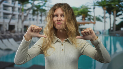 Woman uses her hands to show dislike at a poolside scene with a blonde young figure appearing...