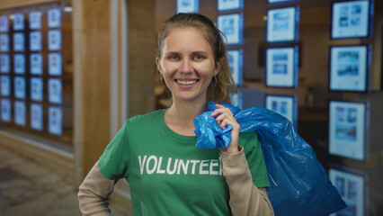 Woman holding a bag and smiling while participating in a cleanup event, blonde young volunteer...