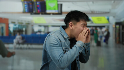 Young man shouting at airport terminal wearing denim jacket inside modern indoor setting with...