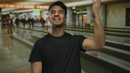 Young hispanic man at airport gesturing good taste, surrounded by indoor terminal bustle,...
