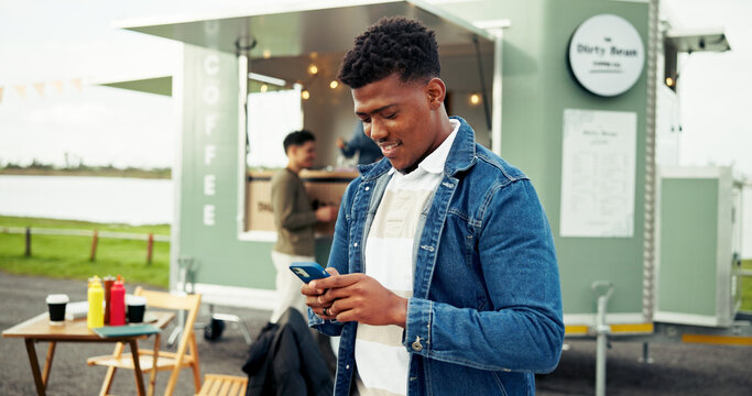 Happy, food truck and man with phone in city on social media, internet and website on weekend. Customer review, outdoor and person typing on smartphone by mobile cafe, restaurant and vendor rating