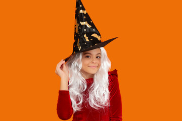 Girl witch in Halloween costume isolated on orange. Trick or treat. All Hallows costume party...
