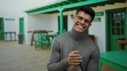 Young man clapping joyfully on an outdoor terrace in a city restaurant, showcasing an attractive...