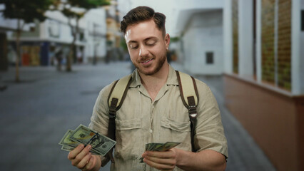 Young man with backpack and camera counts us dollars on a city street showcasing a focus on travel...