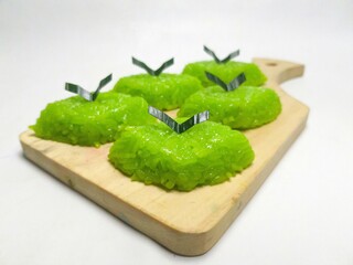 Green sticky rice cake (wajik) layered with pandan leaves, a traditional Indonesian delicacy, arranged on a wooden board. A traditional Indonesian dessert perfect for food-, culture-, or culinary-them