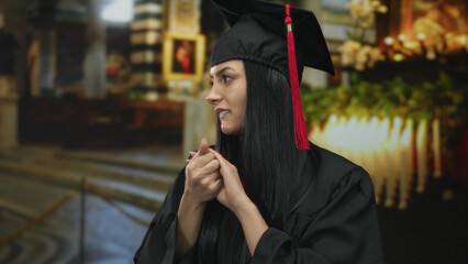 Woman in graduation gown with cap, in church setting, showing nervous expression, suggesting...