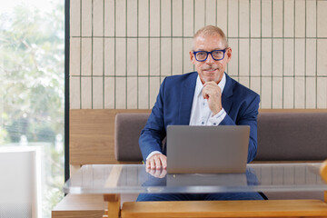 Happy latin hispanic mid aged business man working on laptop computer in company office. Smiling Indian entrepreneur manager man using pc for communication, learning at workplace. Copy space
