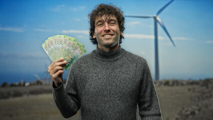 Man smiling outdoors holding russian rubles with a windmill in a field behind him, representing...