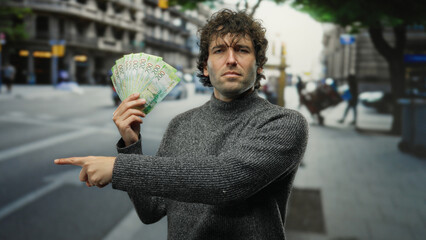 Hispanic man outdoors pointing sideways holding russian banknotes on a busy city street...