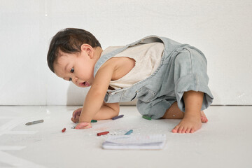 a baby crawling on the floor with crayons in their hands, surrounded by a white background.