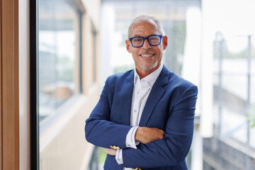Portrait of Happy mature older male entrepreneur standing with crossed arms smiling confident at...