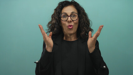 Woman expressing surprise with hands on cheeks against green wall background with shocked...