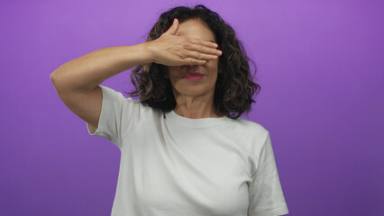 Fototapeta premium Woman smiling with glasses covering eyes on a purple background, wearing a white shirt, expressing playfulness and curiosity, emphasizing middle-aged hispanic female diversity and emotion.