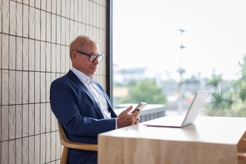 Portrait of a cheerful mid adult businessman using phone for investment plan chatting contact...
