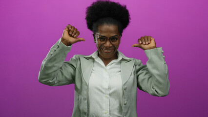 Woman smiling confidently points to herself against an isolated pink background wearing glasses and...