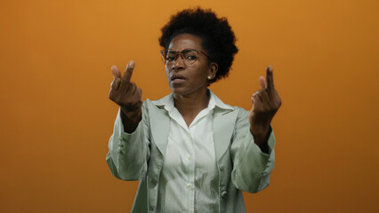 Woman making rude gesture with both middle fingers raised on an isolated orange background,...