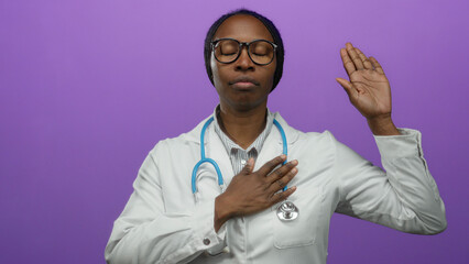 Woman doctor in white coat with stethoscope holding hand to chest against purple background...