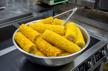 Bright yellow corn on the cob is steamed and arranged in a bowl, ready for serving in a lively...