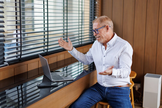 Mature business man executive coach talking using laptop computer having video conference call online meeting, professional training negotiation remote working doing online presentation in office.