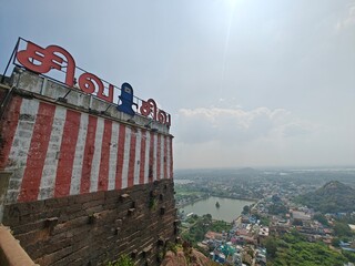 A spiritually resonant view of Thirukazhukundram, Tamil Nadu, India, capturing both the hilltop Vedagiriswarar Temple and the ancient foothill temple complex. The hill temple, dedicated to Lord Shiva,