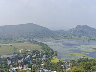 A spiritually resonant view of Thirukazhukundram, Tamil Nadu, India, capturing both the hilltop Vedagiriswarar Temple and the ancient foothill temple complex. The hill temple, dedicated to Lord Shiva,
