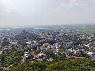 A spiritually resonant view of Thirukazhukundram, Tamil Nadu, India, capturing both the hilltop Vedagiriswarar Temple and the ancient foothill temple complex. The hill temple, dedicated to Lord Shiva,