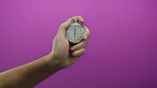 Man holding stopwatch against vibrant pink wall symbolizing precision, timing, and control.