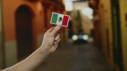 Closeup of a caucasian man's hand holding an embroidered mexican flag patch in a vibrant outdoor...