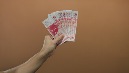 Caucasian man holding serbian banknotes against brown wall background, showcasing money and finance...