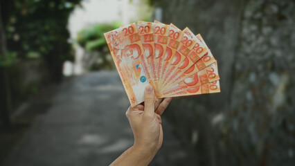 Caucasian man displaying philippine pesos outdoors in a city street, highlighting the vibrant...