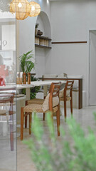 Modern restaurant indoors featuring wooden chairs, decorative lamps, and greenery, providing a cozy and welcoming atmosphere for dining and relaxation.